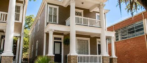 A two-story house with a front porch, columns, and a brick garage.