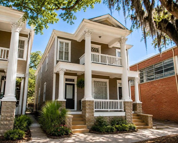 A two-story house with a front porch, columns, and a brick garage.