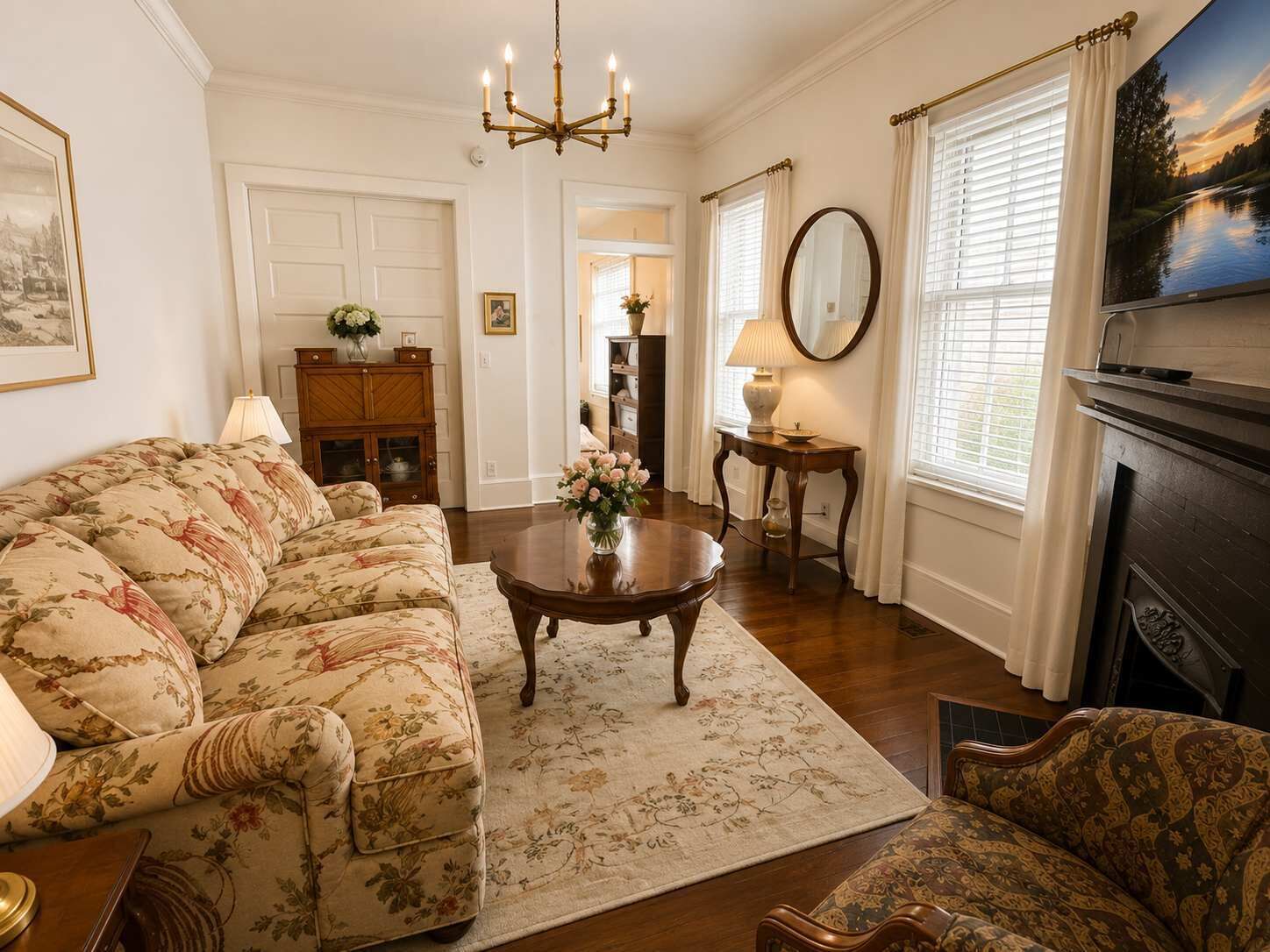 A living room with a floral sofa, a wooden coffee table, a fireplace, and a television.