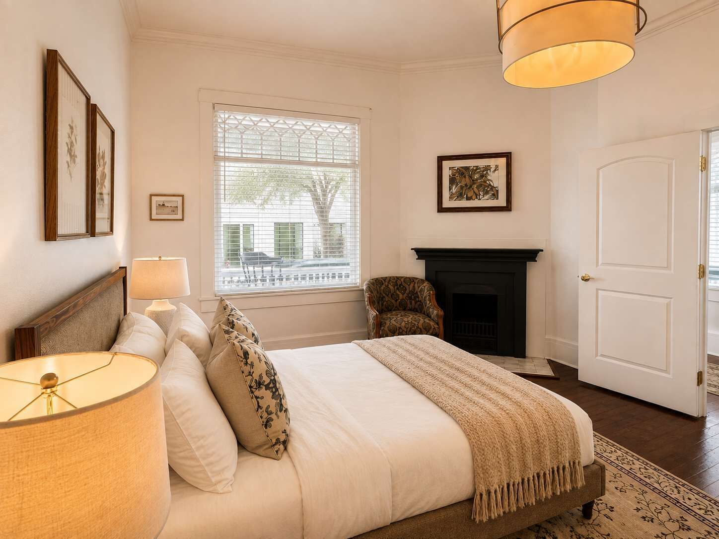 Een slaapkamer met een bed, een stoel, een open haard en een raam met zonwering.