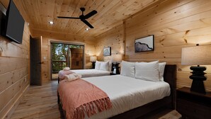 A wooden cabin bedroom with two beds, a ceiling fan, and a TV mounted on the wall. - NEW CABIN: Sauna | Hot Tub | Fire Pit | EV (Gatlinburg)