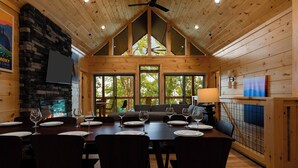 A wooden interior with a dining table set for six, surrounded by chairs. - NEW CABIN: Sauna | Hot Tub | Fire Pit | EV (Gatlinburg)