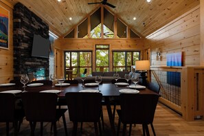 Un interior de madera con una mesa de comedor dispuesta para seis personas, rodeada de sillas.