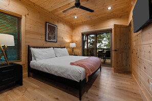 Ein Schlafzimmer mit Holzwänden, einem Bett, Nachttischlampen und einem Deckenventilator.