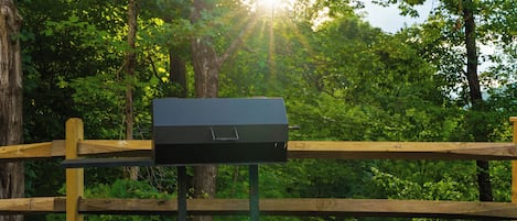 A portable grill on a wooden stand in a wooded area.