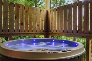 Un jacuzzi con cerramiento de madera, rodeado de follaje.