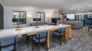 A modern hotel room with a long dining table, multiple chairs, a sofa, and a TV. - Accessible 1BR Suite | Free Daily Breakfast & Pool (Madison)