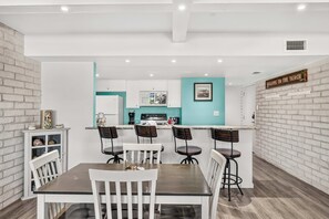 Una cuina moderna amb armaris blancs, una paret d'accent color turquesa i una zona de bar amb tamborets.