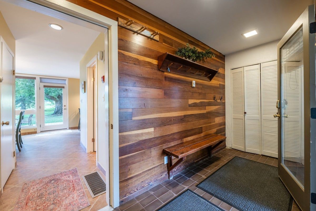 Un couloir avec un mur en bois, un banc et une porte donnant sur une pièce.