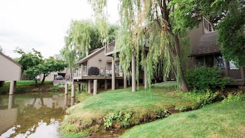 A residential area with houses on stilts over a body of water, surrounded by greenery.
