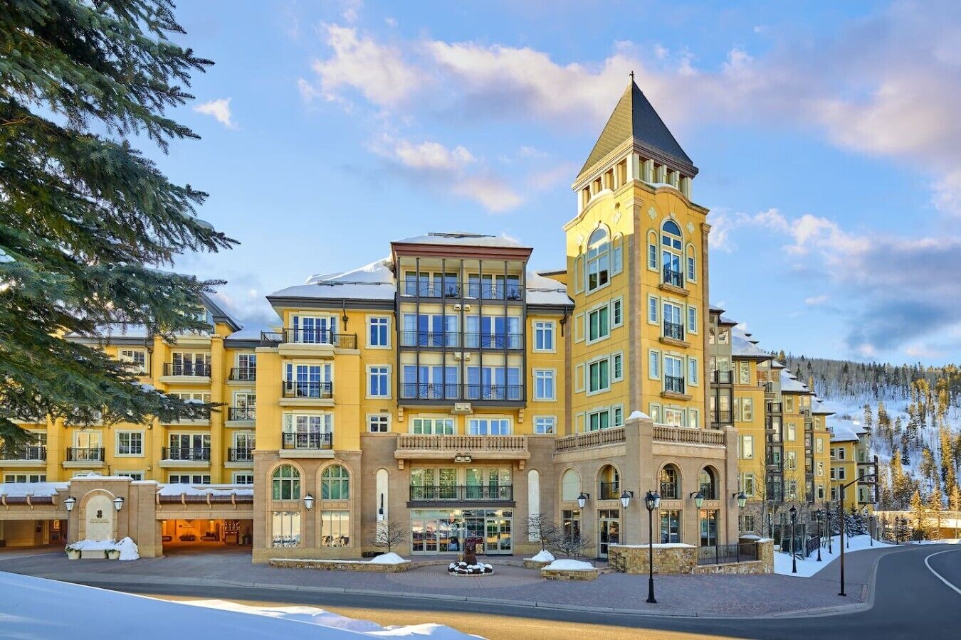 A multi-story hotel with a prominent tower, large windows, and a snow-covered entrance.