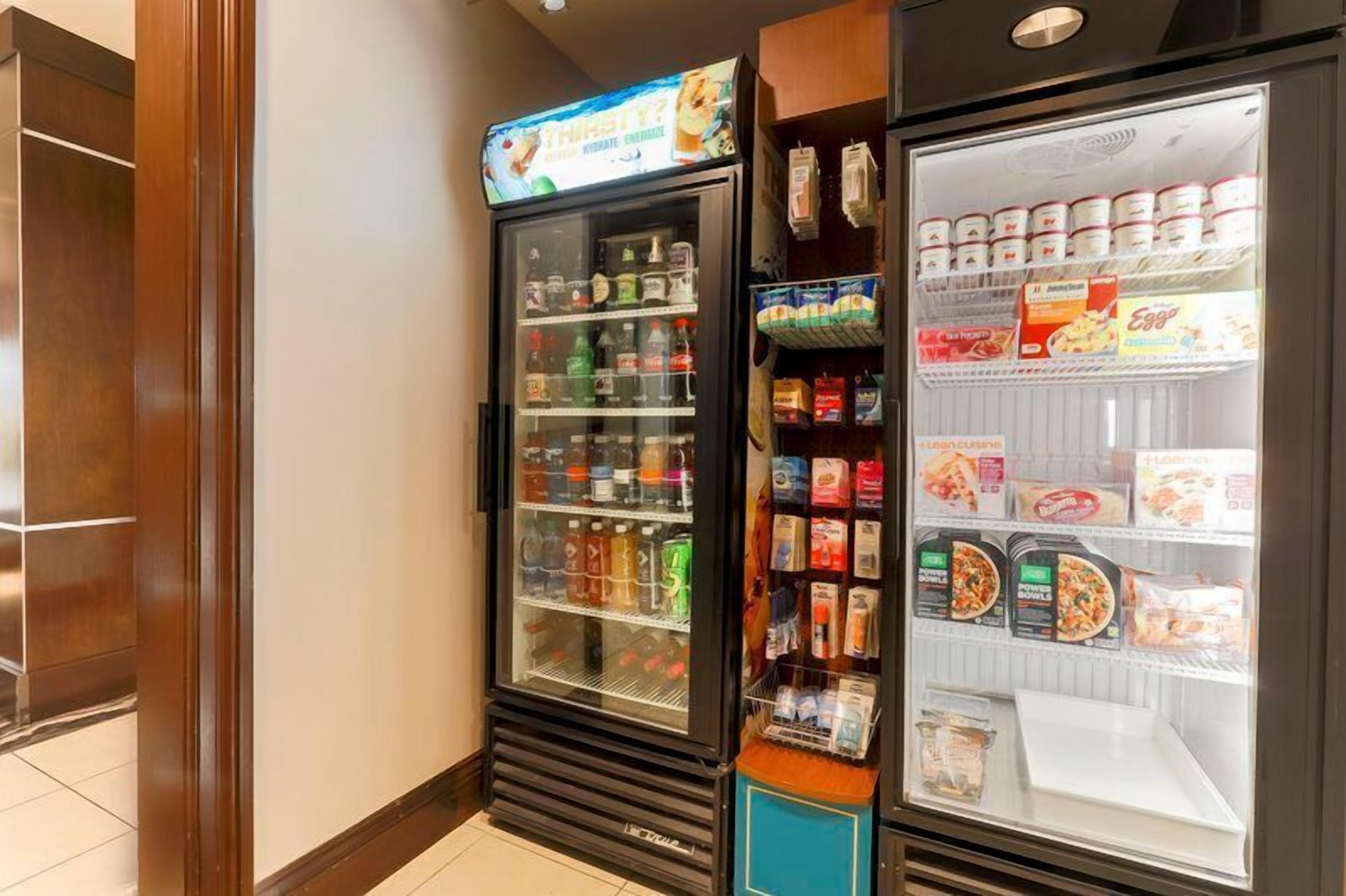 A vending machine with various beverages and snacks, and a refrigerated display case with packaged food items.