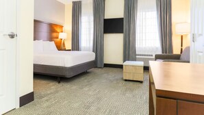 Een hotelkamer met een bed, een bureau, een stoel, een televisie en een raam met gordijnen.
