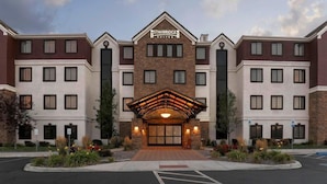 Een Staybridge Suites hotel met een centrale ingang, meerdere verdiepingen en een gevel van baksteen.