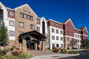 A Staybridge hotel with a brick facade, a covered entrance, and a landscaped front yard.