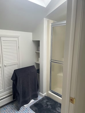 Une salle de bain avec une douche, un porte-serviettes et un sol carrelé.