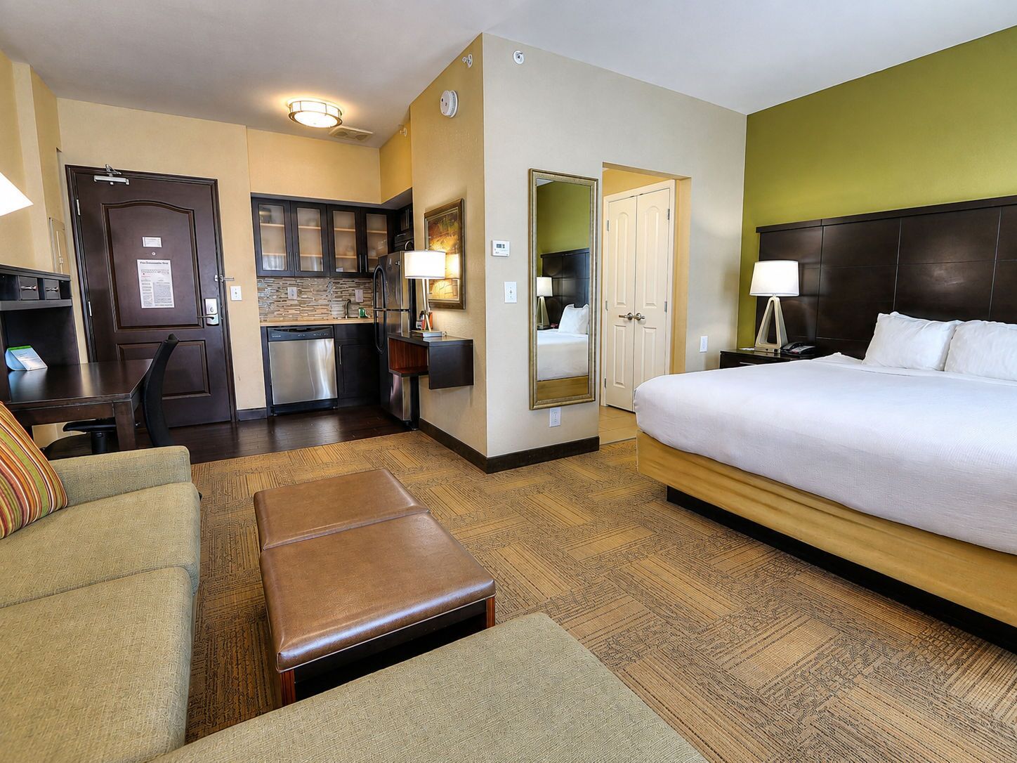Una habitación de hotel con cama, escritorio, kitchenette y baño.