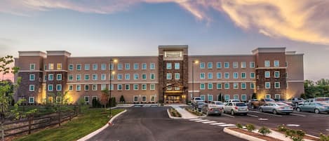 A Staybridge hotel with a central entrance, multiple parking spaces, and a landscaped driveway.