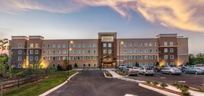 A Staybridge hotel with a central entrance, multiple parking spaces, and a landscaped driveway.