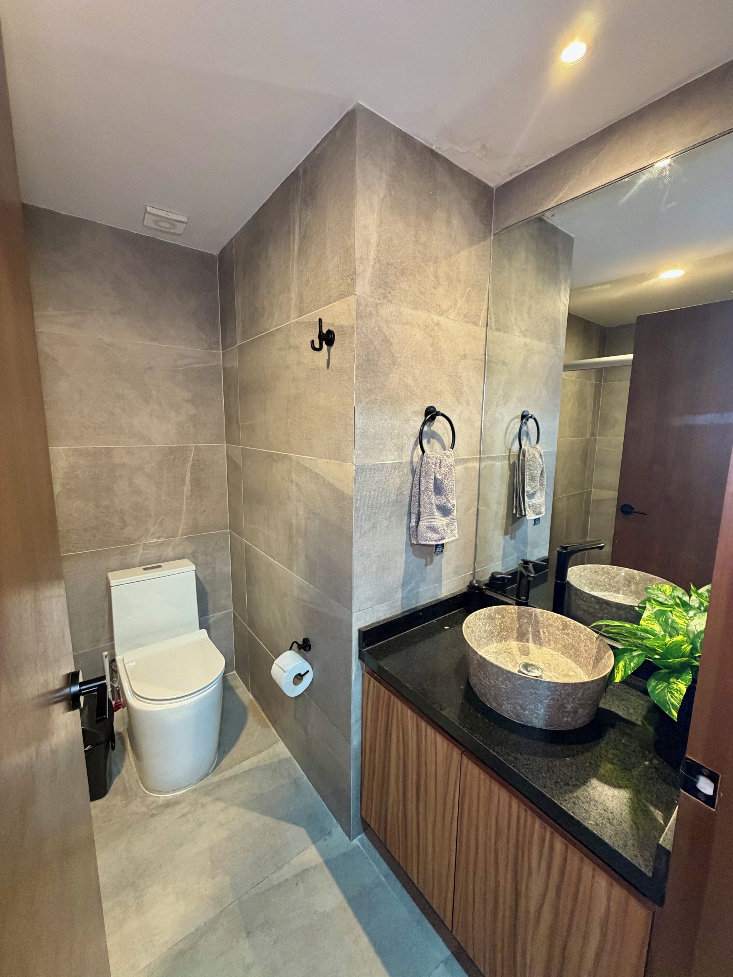 Ein modernes Badezimmer mit Toilette, Bidet und zwei Waschbecken mit einem großen Spiegel darüber.