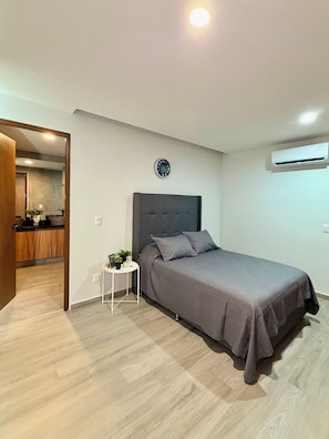 A bedroom with a bed, a bedside table, a clock, and an air conditioning unit. - Agave House | panoramic view | near Andares and hospitals (Zapopan)