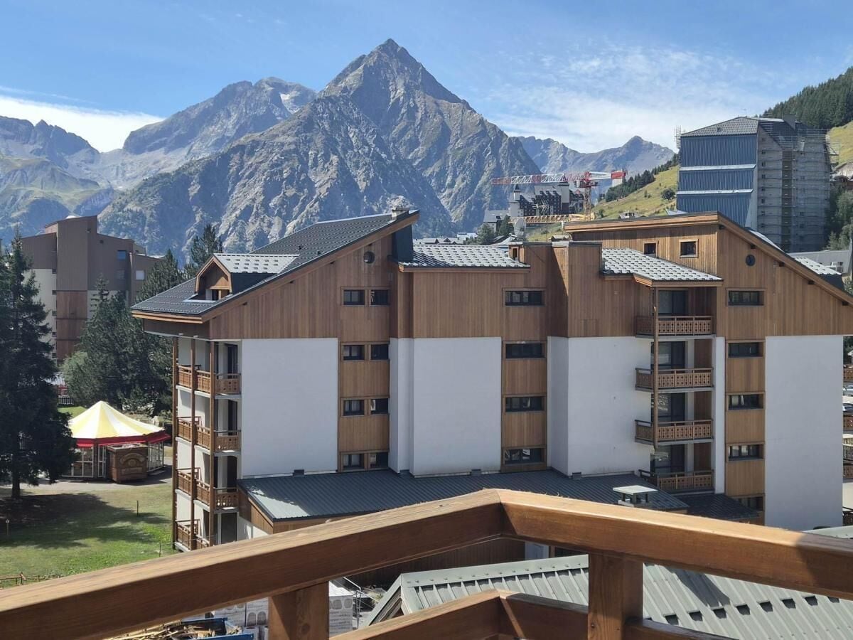 A multi-story building with a wooden facade and balconies, set against a mountainous backdrop.