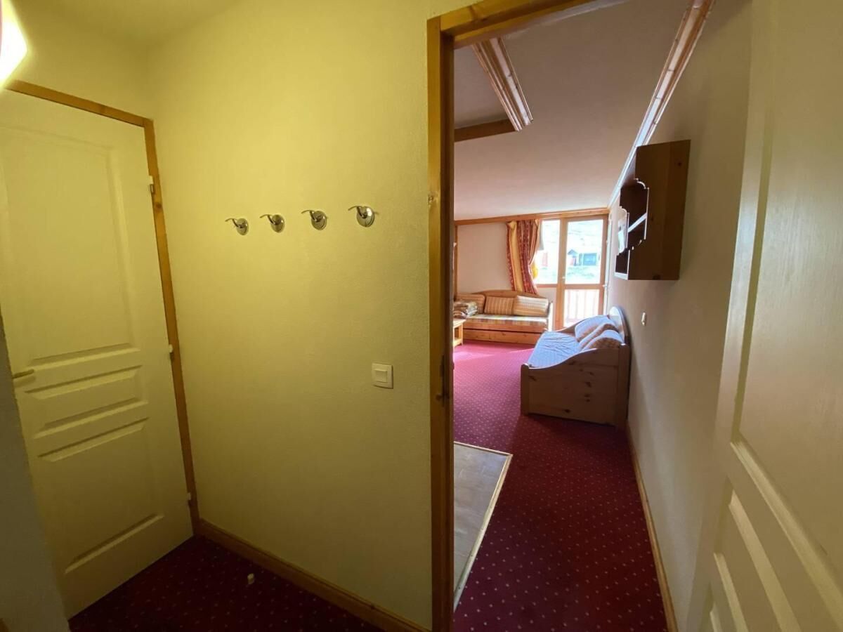 Un couloir menant à une chambre à coucher qui contient un lit, une fenêtre et une porte.