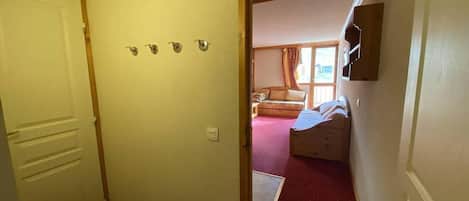 Un couloir menant à une chambre à coucher qui contient un lit, une fenêtre et une porte.