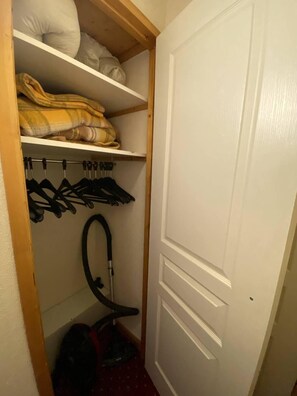 A closet with shelves, a hanging rack, and a vacuum cleaner. - 20m from ski slopes, 2nd floor, balcony, 20m², La Plagne (La Plagne)