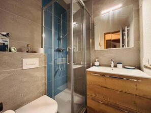 A modern bathroom with a glass shower enclosure, a wooden vanity, and a large mirror. - 50m from ski slopes, 3rd floor, tv, ski locker, 41m², Montchavin La Plagne (Bellentre)