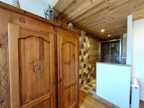 A wooden cabinet with decorative carvings, a white refrigerator, and a hexagonal patterned wall. - 200m from ski slopes, 1st floor, balcony, ski locker, 54m², Valmorel (Valmorel)