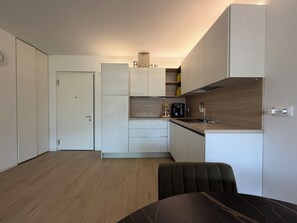 A modern kitchen with white cabinetry, a built-in oven, and a coffee machine. - CasaRipa, one-bedroom apartment with olive grove view, 5 minutes from the lake (Riva del Garda)