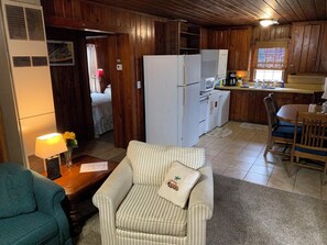 A compact living space with a kitchenette, a dining area, and a seating area with a striped sofa and a small table.