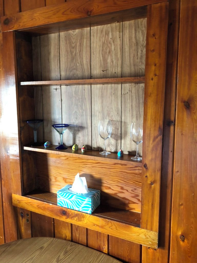 A wooden shelf with decorative glassware and a tissue box.