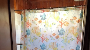 A bathroom with a shower curtain featuring a fish pattern, a toilet, a sink, and a rug with fish designs. - 2-bedroom cottage with AC in welcoming Kitty Hawk (Kitty Hawk)