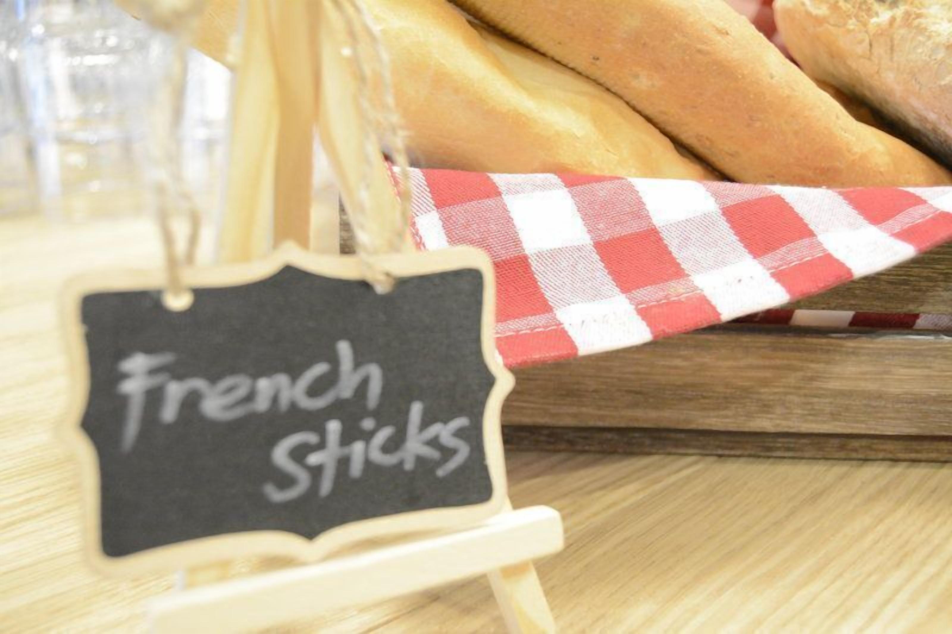 A sign labeled 'French Sticks' on a wooden stand.