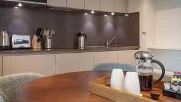 A modern kitchen with a Bosch microwave, a coffee maker, and a dining table with a tray of cups and a coffee pot.