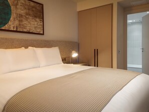 Una habitación de hotel con una cama grande, una mesita de noche con lámpara y un armario.