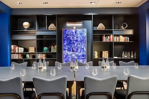 Un salón de conferencias con una larga mesa, sillas y estanterías.