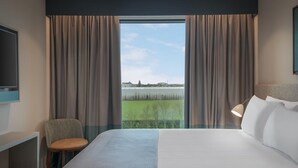 Une chambre d’hôtel avec un grand lit, un bureau, une chaise et une vue sur une étendue d’eau.