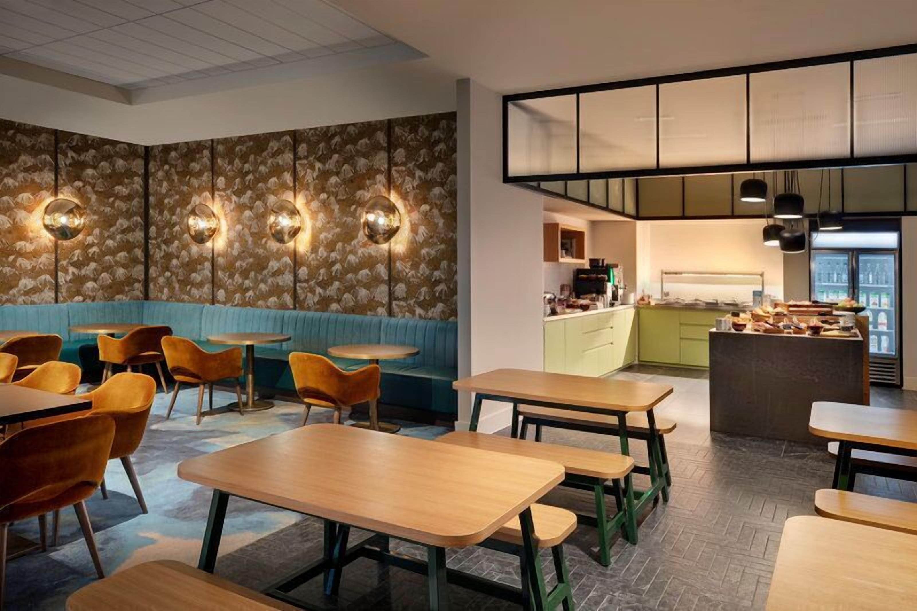 A restaurant with booths, tables, and a kitchen area.