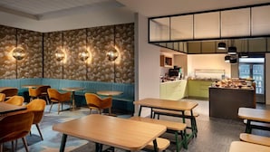 Un restaurant avec des banquettes, des tables et un espace cuisine.