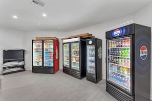 A room with three beverage vending machines, a bed, and a wall-mounted shelf. - Tranquil Spot Near Disney + Pool + BBQ (Kissimmee)