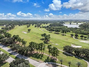 A golf course with sand bunkers, trees, and a clear sky. - Elite Blue King Room 7 min Disney + Free Parking (Kissimmee)