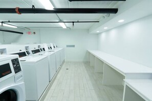 A laundry facility with multiple washing machines and a bench. - Lux King Room 7 min to Disney w/Pool+ Free Parking (Kissimmee)