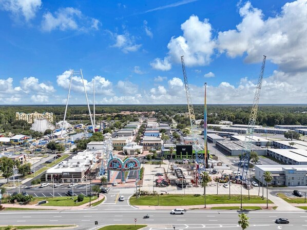A commercial area with multiple buildings, a prominent Ferris wheel, and construction cranes. - Luxurious Apt - 1BR Near Disney + Free Parking (Kissimmee)