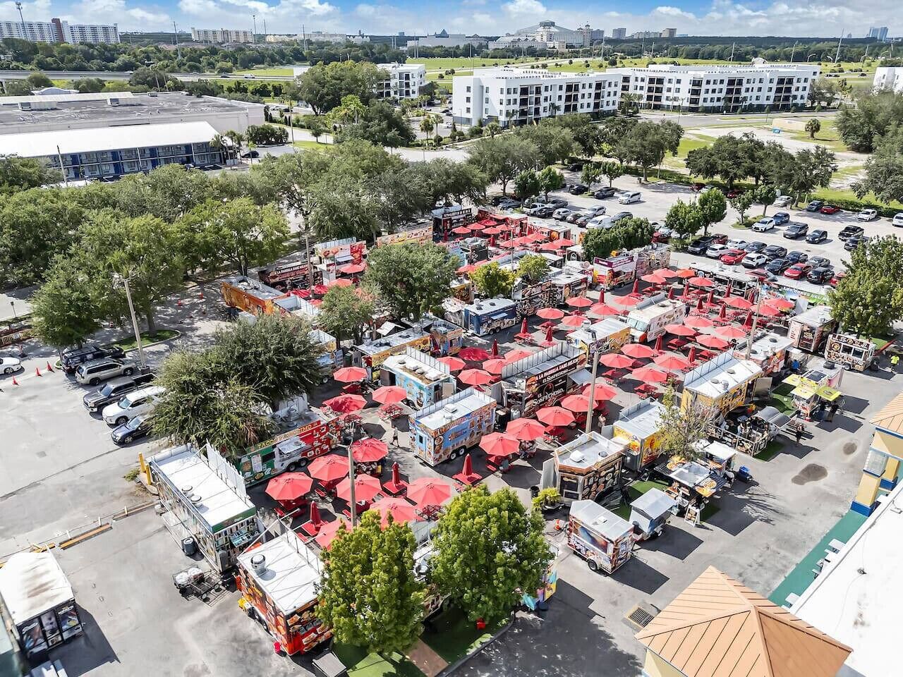 Ein Parkplatz mit mehreren Imbisswagen und roten Sonnenschirmen.
