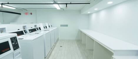 A laundry facility with multiple washing machines and a bench.