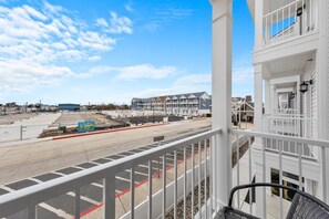A balcony with a view of a street, buildings, and a clear sky. - 2 Lux Homes, Game Rooms, Pool, Bikes, 10 Balconies (Ocean City)