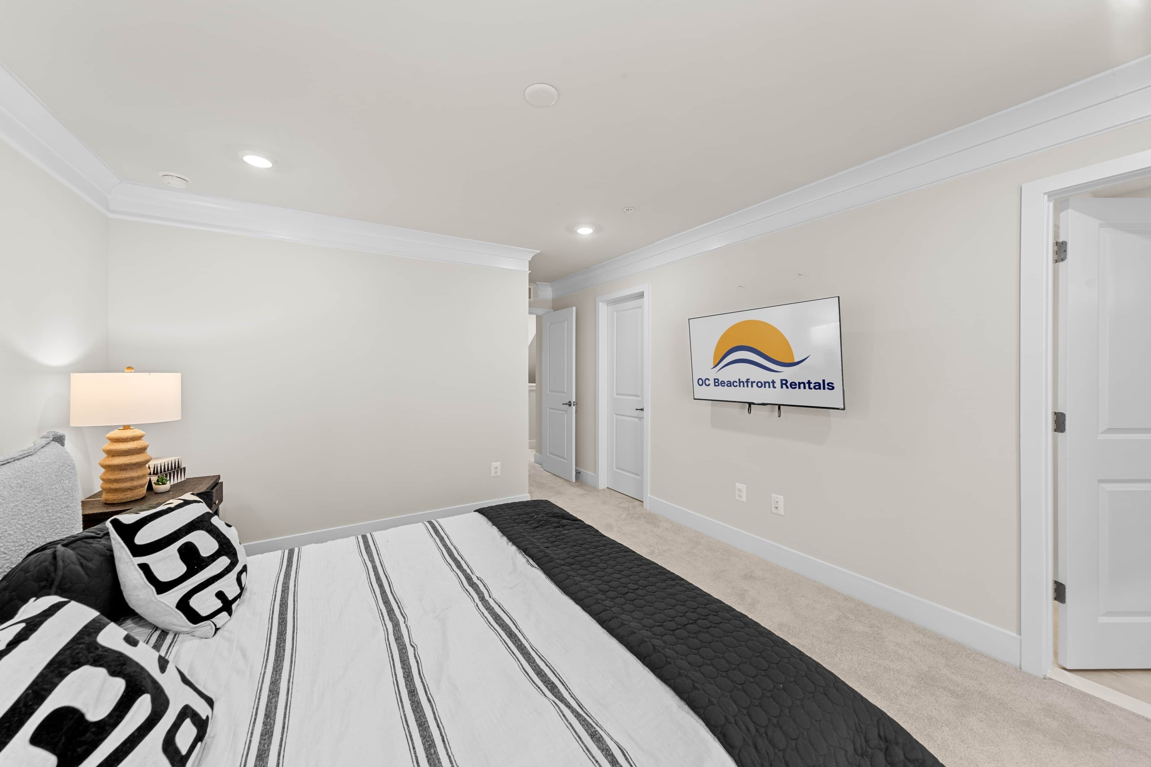 A hotel room with a bed, a TV mounted on the wall, and a door.